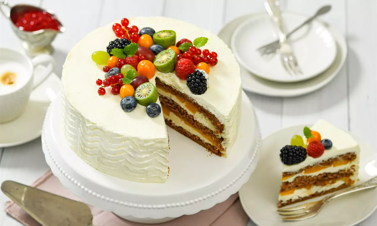 Gâteau rond aux couches mascarpone et génoise dorée garni de fruits éclatants sur un plateau blanc et une assiette assortie